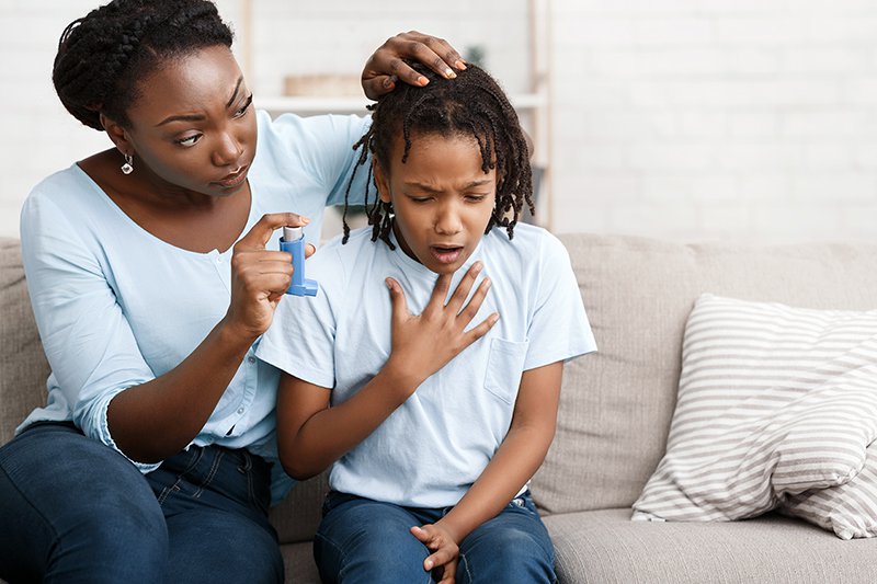 Afro mother holding asthma inhaler for daughter