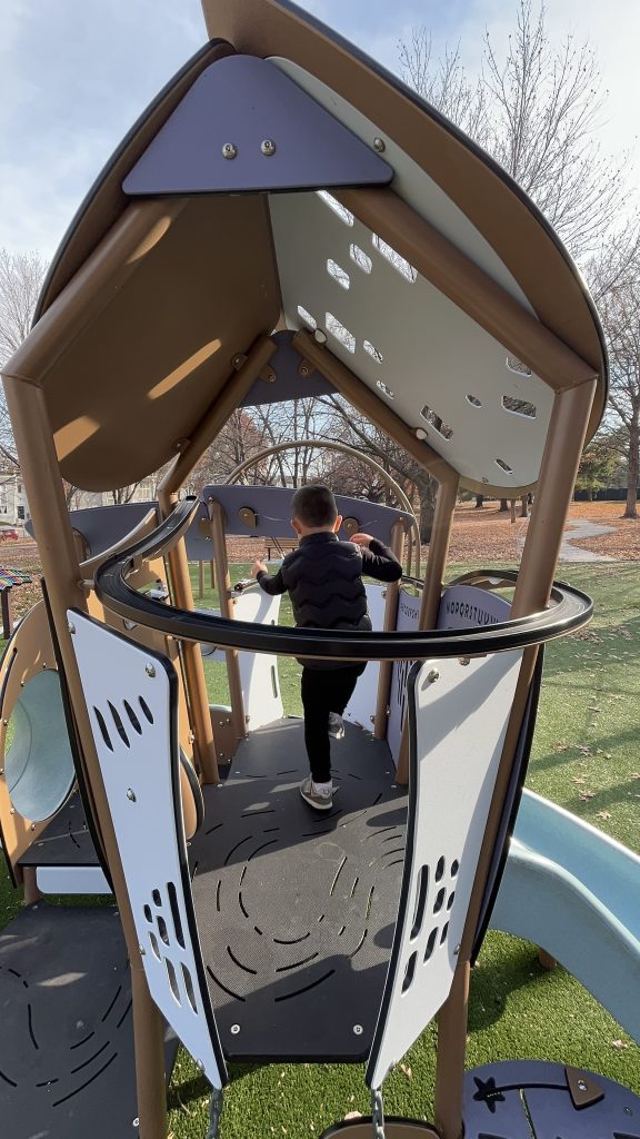 Child playing on the Hot wheels race car track at Maple Hills Park play ground in Overland Park, KS
